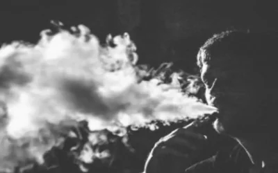 Une personne dans le noir qui crache une grosse quantité de vapeur.