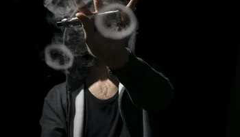 Une personne faisant des ronds avec sa vepeur de cigarette électronique.